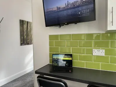a laptop on a table with a tv on a wall at Modern 1 bed studios for comfy stay in Preston in Preston