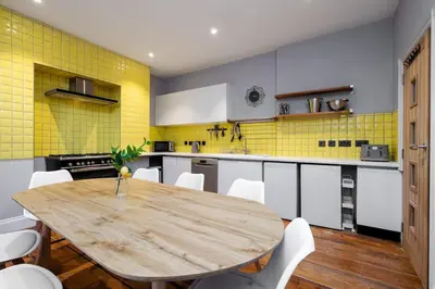 a kitchen with a wooden table and yellow tiles at RST Bramley Moore in Liverpool