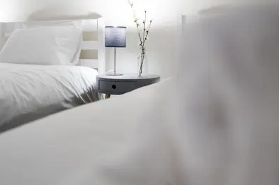 a bedroom with a white bed and a table with a lamp at RST Bramley Moore in Liverpool