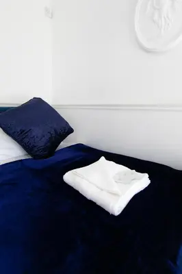 a bed with a blue blanket with a white towel on it at The New Apollo Hotel in Blackpool