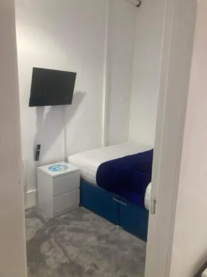 a small room with a bed and a night stand at The New Apollo Hotel in Blackpool