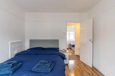 a white bedroom with a blue bed with blue pillows at Cheerful and modern 3 BDR for 7 in Liverpool
