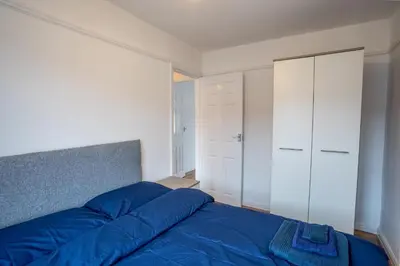 a bedroom with a blue bed and white cabinets at Cheerful and modern 3 BDR for 7 in Liverpool