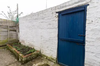 a blue door on the side of a brick wall at Cheerful and modern 3 BDR for 7 in Liverpool