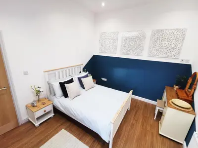 a bedroom with a white bed and a blue wall at The Bakery in Pilling