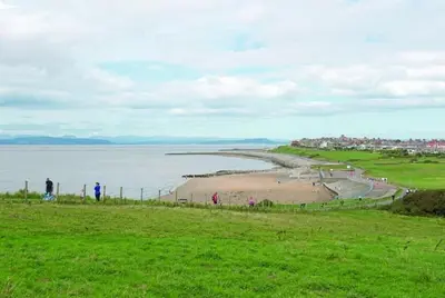 a group of people walking on a beach near the water at The Bakery in Pilling