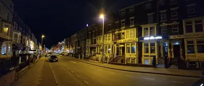 a motorcycle driving down a city street at night at Sleep Well Hotel in Blackpool
