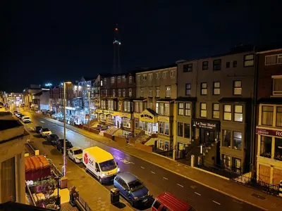 a city street at night with cars parked at Sleep Well Hotel in Blackpool