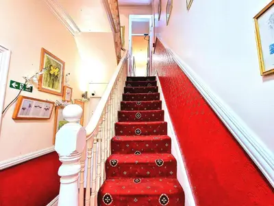 a red carpeted staircase with a red carpet at Sleep Well Hotel in Blackpool