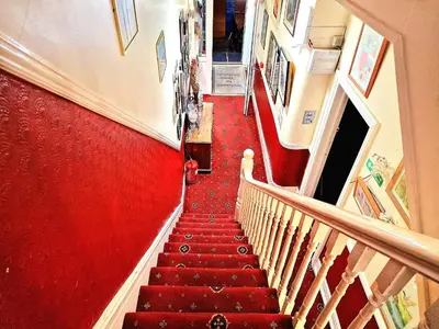 a staircase with red carpeting and a red wall at Sleep Well Hotel in Blackpool