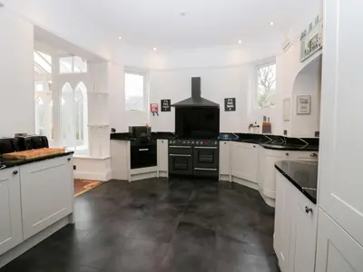 a large kitchen with white cabinets and black appliances at Valley View in Dalton in Furness