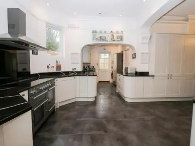 a large kitchen with white cabinets and black appliances at Valley View in Dalton in Furness