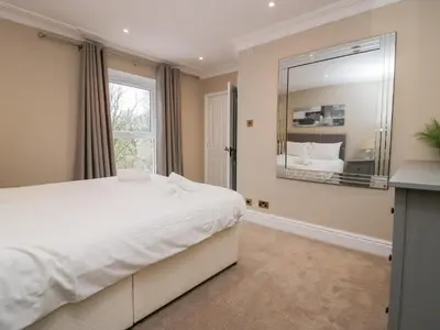 a bedroom with a large white bed and a large mirror at Valley View in Dalton in Furness