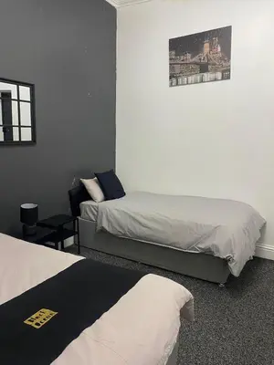 a hotel room with two beds and a chair at Black Ocean Holiday Apartments in Blackpool