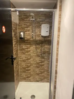 a shower in a bathroom with a brick wall at Black Ocean Holiday Apartments in Blackpool