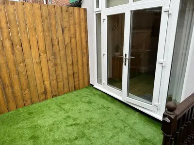 a patio with green grass next to a wooden fence at Watford Road House Liverpool in Liverpool