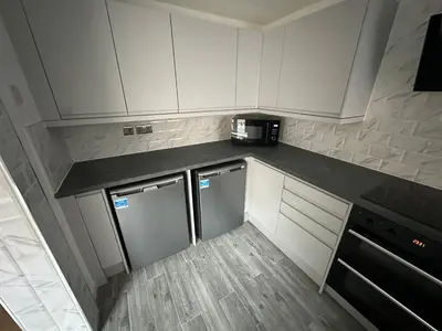 a kitchen with white cabinets and a black counter top at Watford Road House Liverpool in Liverpool