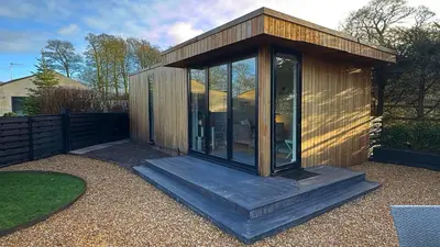 a small wooden cabin with glass doors in a yard at Oakdean Lodge in The Ribble Valley in Whalley