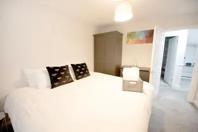 a bedroom with a large white bed with pillows at Garden by the Bay Southport in Southport