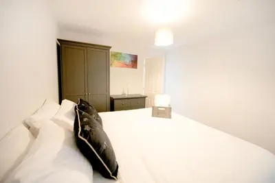 a bedroom with a white bed with a black pillow at Garden by the Bay Southport in Southport
