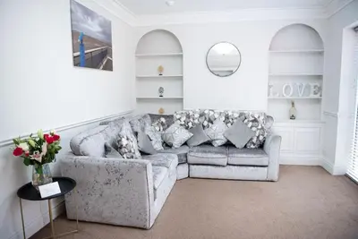 a living room with a couch and a vase of flowers at Garden by the Bay Southport in Southport