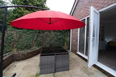 a red umbrella sitting on top of a patio at Garden by the Bay Southport in Southport