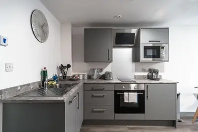 a kitchen with stainless steel appliances and a clock on the wall at Lovely 1 Bed Apartment in Central Liverpool in Liverpool
