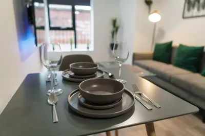a table with two plates and wine glasses on it at Lovely 1 Bed Apartment in Central Liverpool in Liverpool
