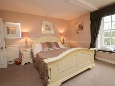 a bedroom with a large bed and two lamps and a window at Old Book Shop in Grange Over Sands