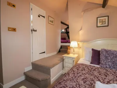 a bedroom with a bed and a stairway with a door at Old Book Shop in Grange Over Sands