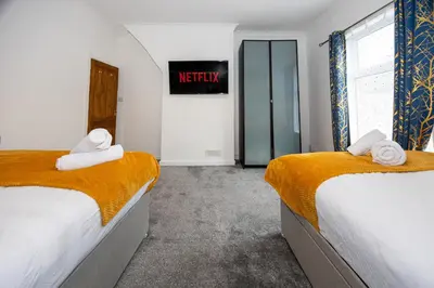 two beds in a room with a sign on the wall at Cosy Two bedroom Terrace Blackburn in Cherry Tree