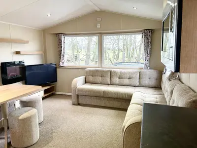 a living room with a couch and a tv at The SandyBel Caravan in Cark