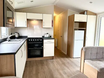 a kitchen with white cabinets and a stove top oven at The SandyBel Caravan in Cark