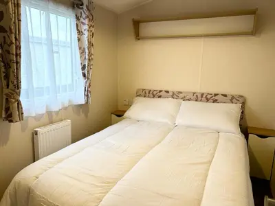 a large bed in a bedroom with a window at The SandyBel Caravan in Cark