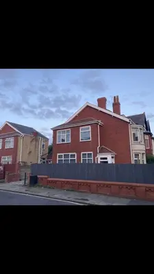a red brick house with a fence in front of it at Danny holiday home in Blackpool