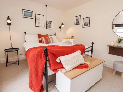 a bedroom with a bed with a red blanket on it at Tilly's Place in Heysham
