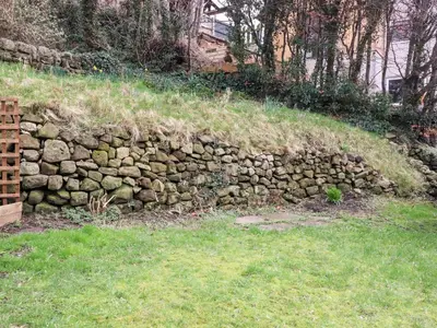 a stone wall in a field with grass at Tilly's Place in Heysham