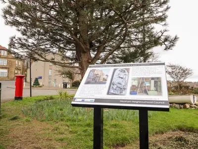 a sign in the grass in front of a tree at Tilly's Place in Heysham