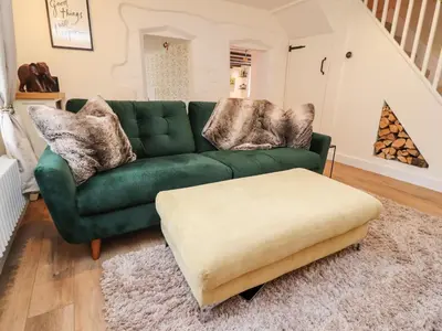 a living room with a green couch and a ottoman at Tilly's Place in Heysham
