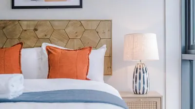 a bedroom with a bed with orange pillows and a lamp at Host & Stay - The Baltic Penthouse 2 in Liverpool