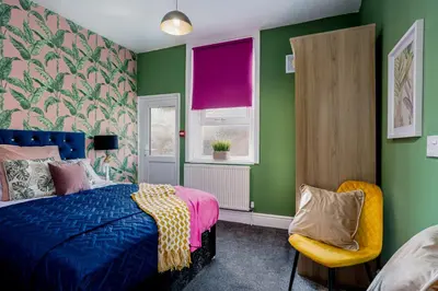 a bedroom with green walls and a bed and a chair at Charles Alexander Short Stay - Botanical House in Cleveleys