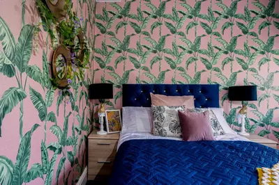a bedroom with a blue bed with a floral wallpaper at Charles Alexander Short Stay - Botanical House in Cleveleys