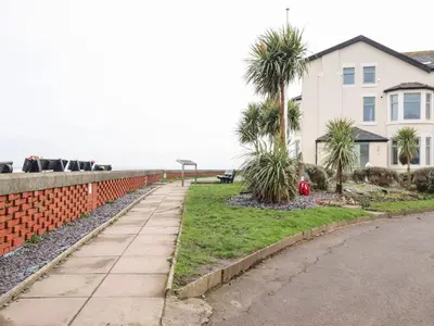 a sidewalk next to a house with palm trees at Ferry View in Fleetwood