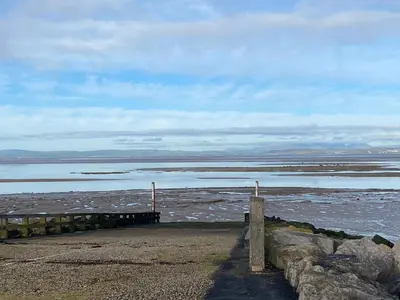a beach with a pier and a body of water at The Cellar on Hornby in Morecambe