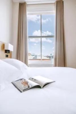 a book laying on a bed with a window at School Lane Hotel in Liverpool ONE in Liverpool