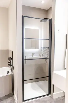 a glass shower door in a bathroom with a sink at School Lane Hotel in Liverpool ONE in Liverpool
