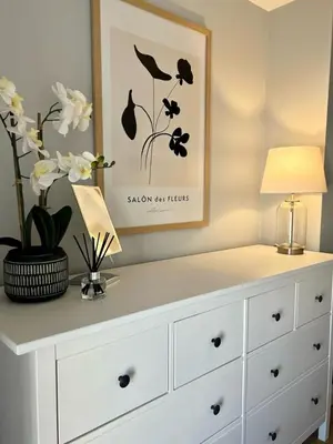 a white dresser with a lamp and flowers on it at Prince Arthur Apartment in Walton on the Hill