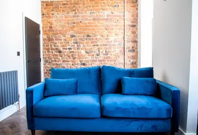 a blue couch in front of a brick wall at Withnell Stays - Apartment Four - Ground Floor in Blackpool