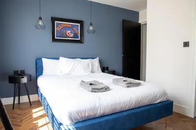 a blue bedroom with a bed with towels on it at Withnell Stays - Apartment Four - Ground Floor in Blackpool