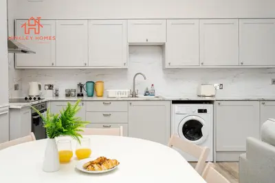 a white kitchen with a plate of food on a table at Large City Centre Apartment - Georgian Townhouse- Rodney St in Liverpool